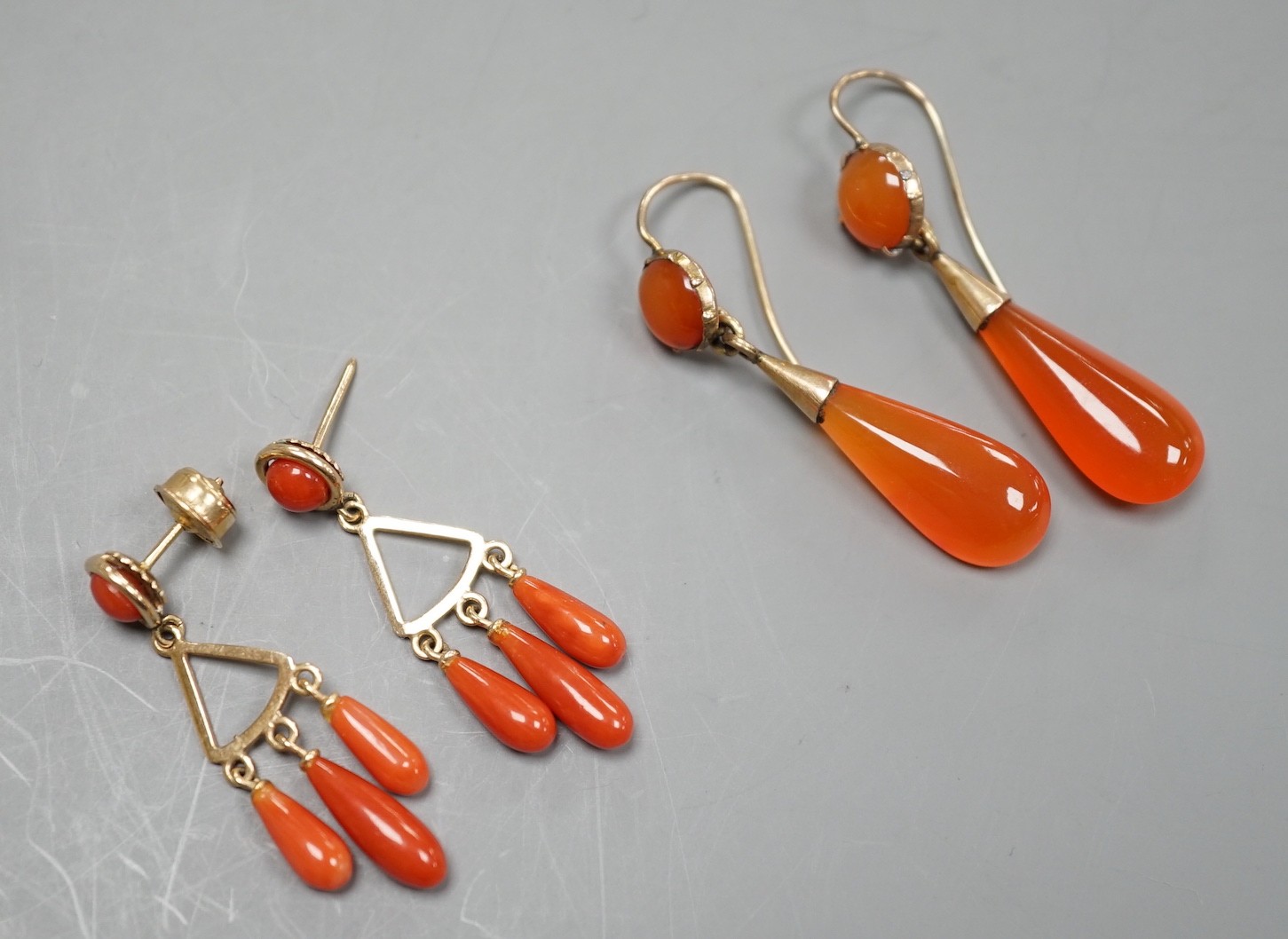 A pair of yellow metal and triple drop coral earrings, overall 37mm, gross 4.4 grams and a pair of carnelian set drop earrings.